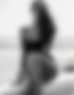 Фото Девушка в черном купальнике сидит на тротуаре, на фоне пляжа