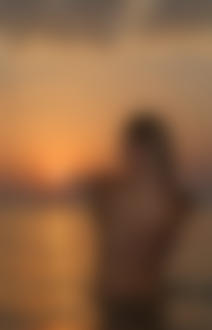 Фото Девушка стоит в воде спиной к нам и пальцем руки дотрагивается к солнцу