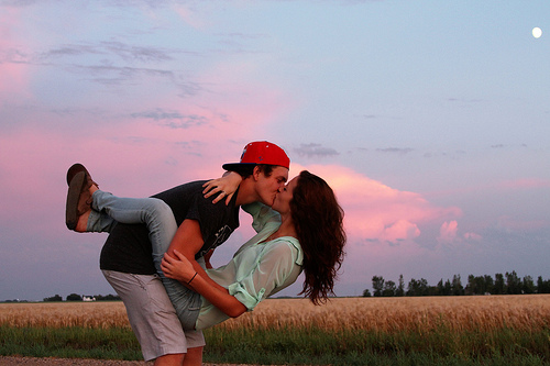 Фото Мужчина целует девушку, подняв ее на руки, в поле