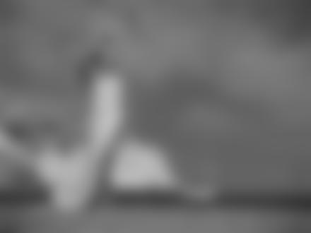 Фото Девушка в легкой белой ткани, стоит на берегу моря, позади виднеется катер