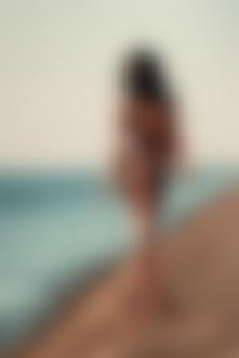 Фото Девушка в сетчатом платье идет по берегу моря