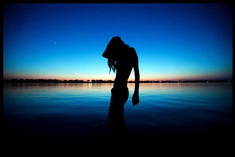 Фото Силуэт девушки, стоящей в воде на фоне вечернего голубого неба, фотограф Timothy Keen