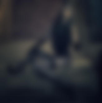 Фото Гламурная девушка с черной маской на лице эффектно выпускает изо рта струйку дыма, сидя на диване с сигаретой в руке, фотограф Jan Hronsky