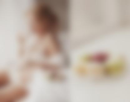 Фото Девушка в нижнем белье пьет чай, сидя у кровати, рядом стоит блюдце с пирожными