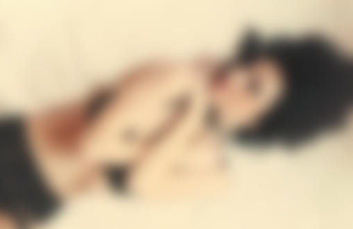 Фото Девушка в черном белье лежит на кровати, обхватив себя руками