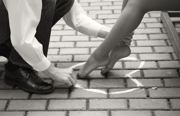 Фото Влюбленный парень ставит ножки любимой девушки в нарисованное мелом на тротуарной плитке сердце