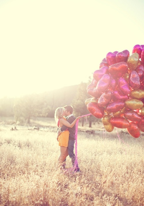 Фото Мужчина с девушкой стоят в поле, девушка в руках держит воздушные шарики