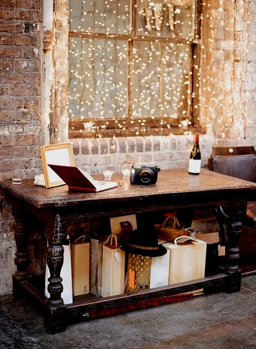 Фото Окно в доме, украшенное горящей гирляндой фонариков и рядом стоящим столом, заполненным различными предметами интерьера