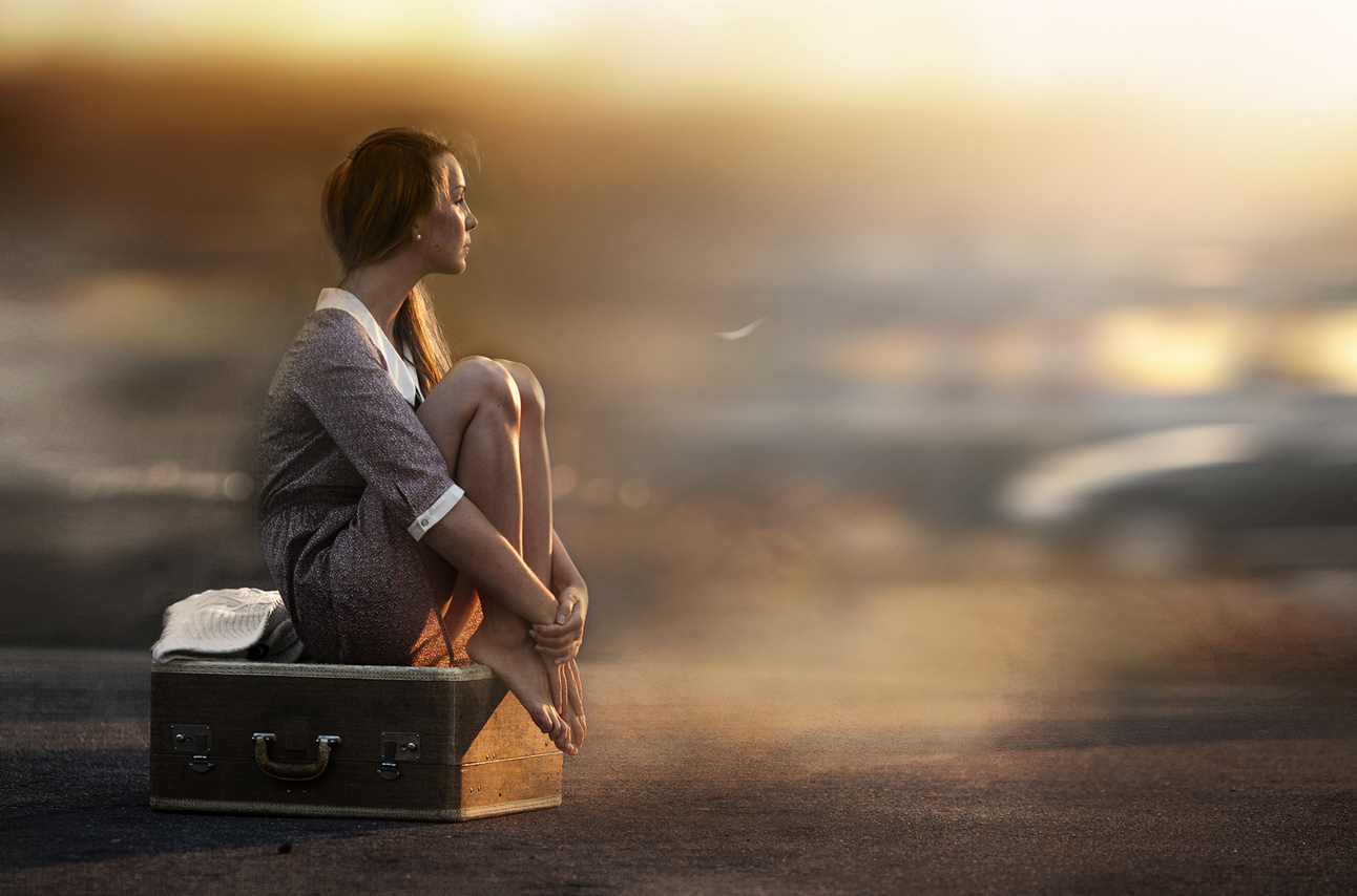 Фото Мечтательная девушка сидит на чемодане поджав ноги на улице. Фотограф Елена Шумилова / Elena Shumilova