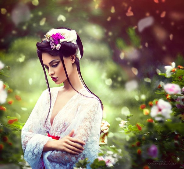 Фото Девушка в белой кофточке сложила руки у груди стоя на фоне летающих лепестков цветов, фотограф Margarita Kareva