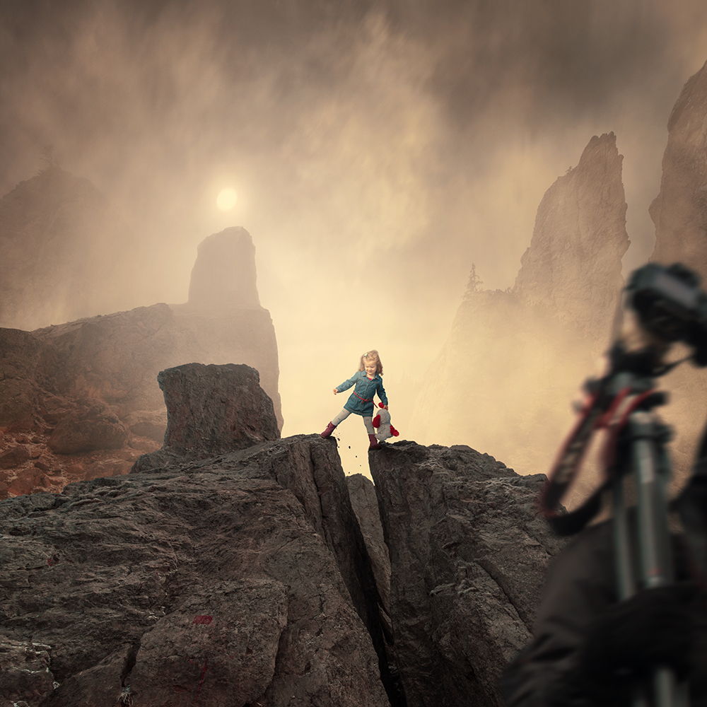 Фото Маленькая девочка, держащая в руках мягкую игрушку, стоит над расщелиной в горах, автор Garas Iount