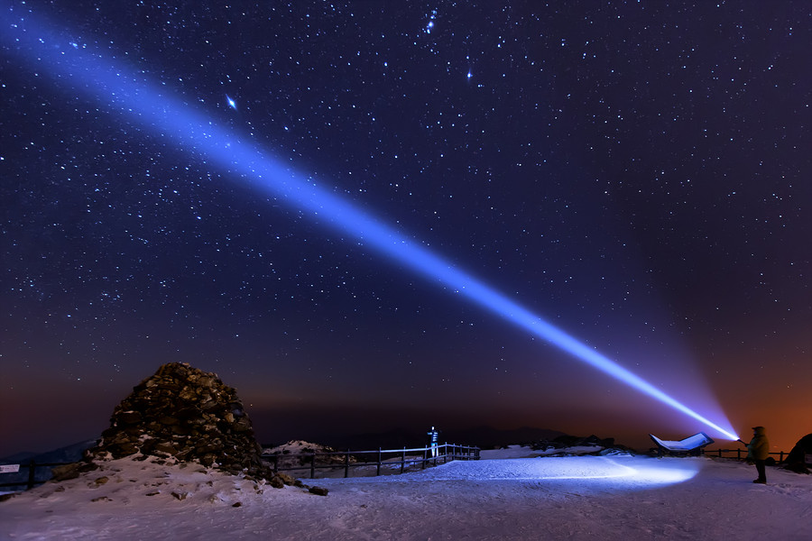 Фото Мужчина с фонарем, луч которого направлен на звездное зимнее небо, фотограф HeungSoon