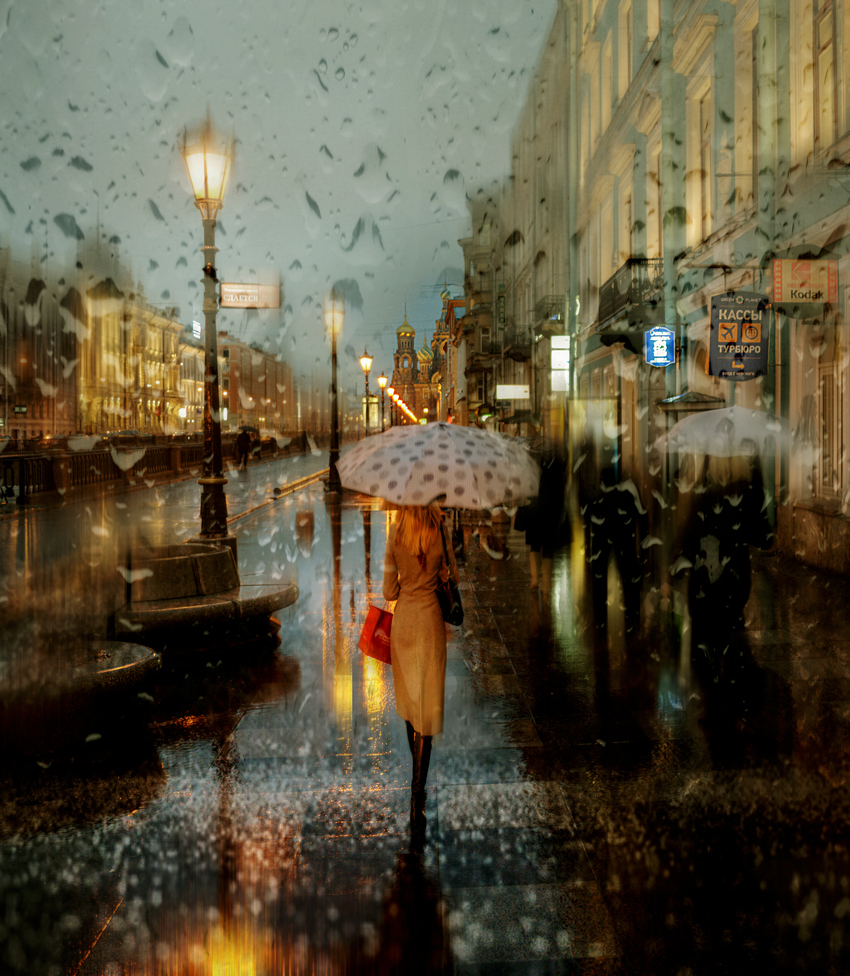Фото Стройная девушка в плаще, держащая в руке зонт, идущая под дождем по городскому тротуару залитому водой, фотохудожник Эдуард Гордеев