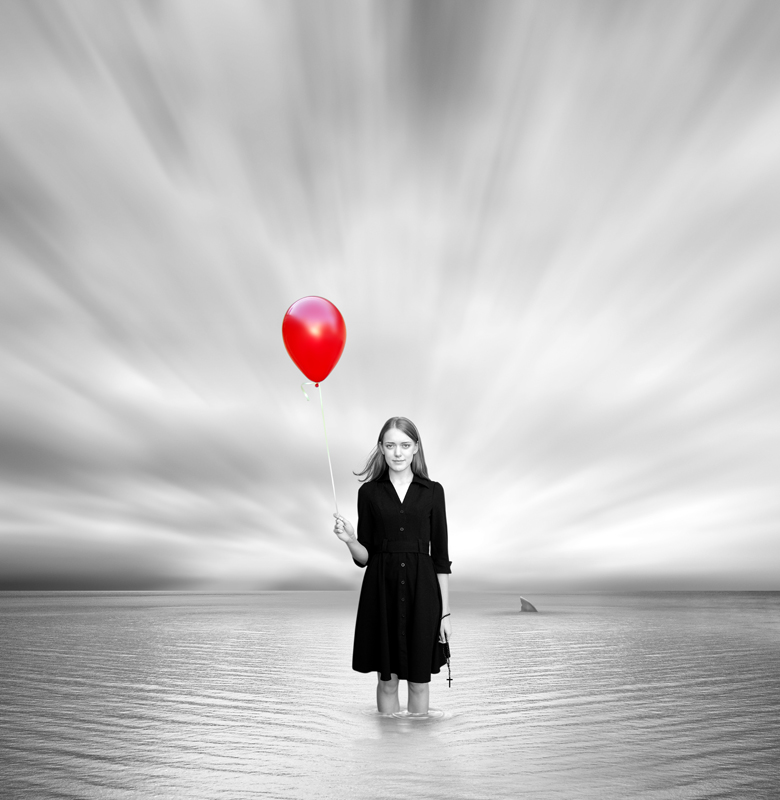 Фото Черно-белое фото девушки с красным шариком, стоящей в воде на фоне неба