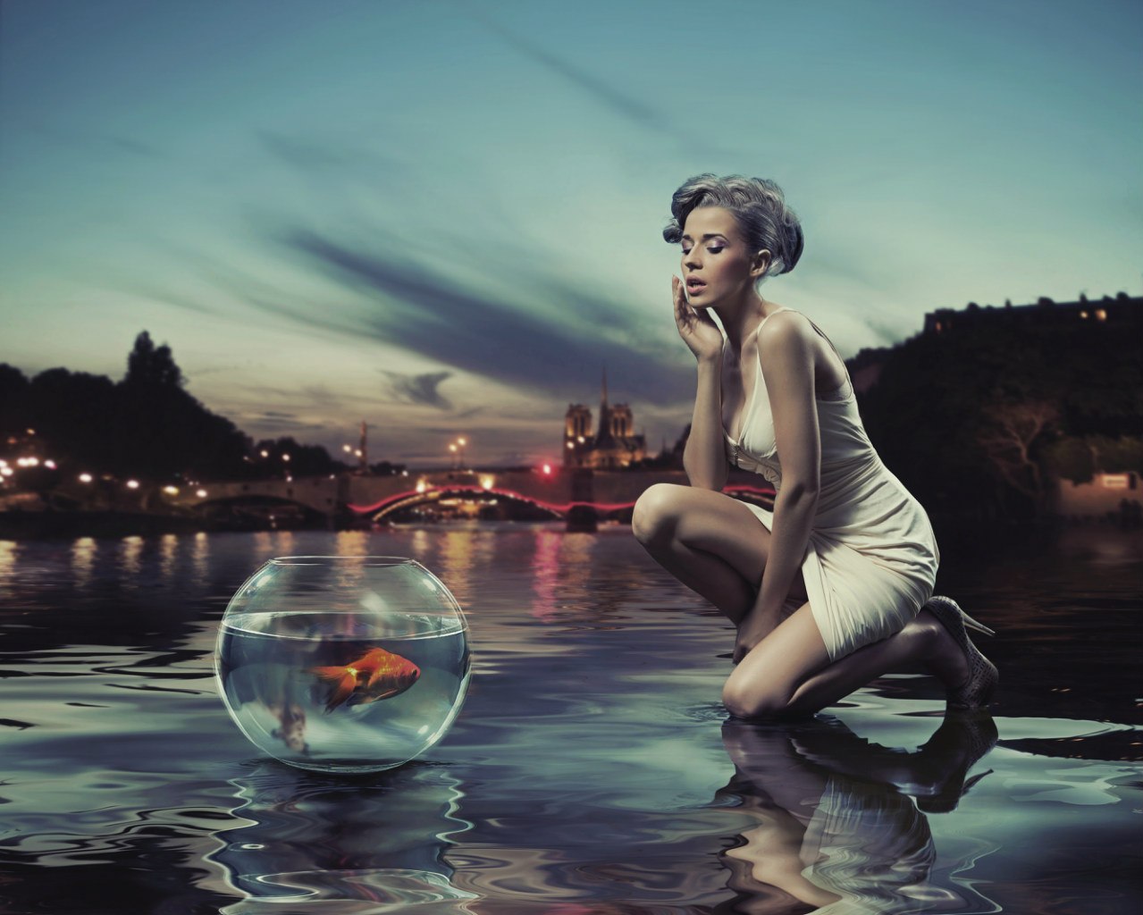 Фото Девушка в воде на фоне ночного города, рядом с ней стоит аквариум с золотой рыбкой