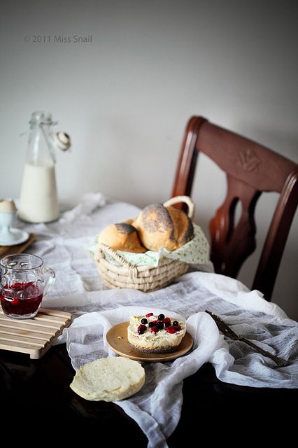 Фото Корзина с булочками, варенье и бутылка с молоком на столе