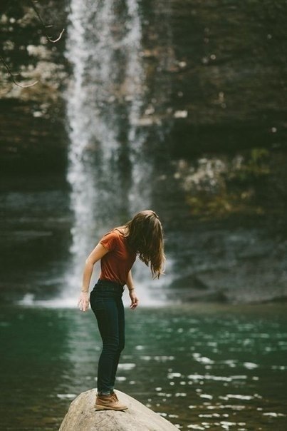 Фото Девушка стоит на камне на фоне водопада