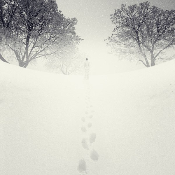 Фото Человек уходит вдаль, оставляя следы на снегу