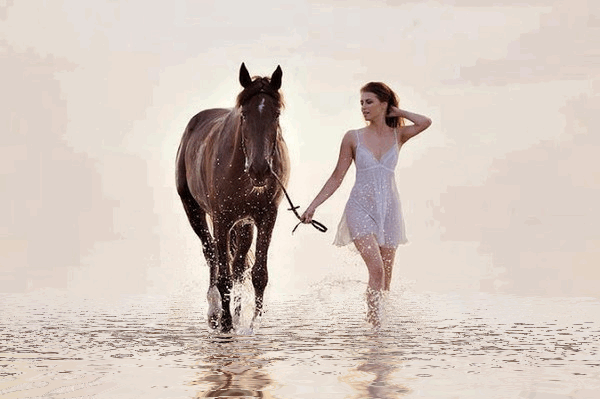 Фото По берегу реки идет девушка в белом сарафане, рядом с ней конь, которого она держит за повод