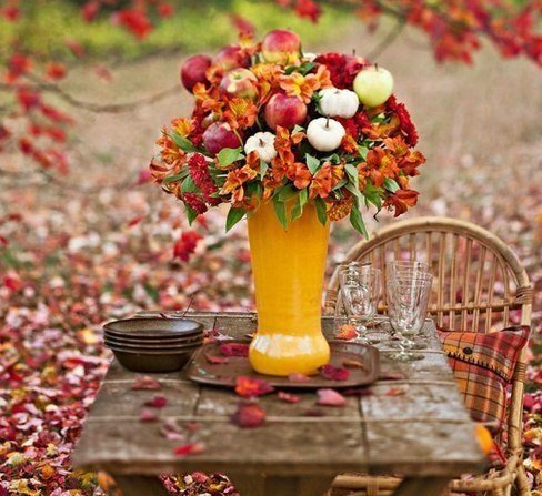 Фото Букет из осенних цветов, листьев и спелых яблок стоит на столе на  природе, посреди опавшей листвы