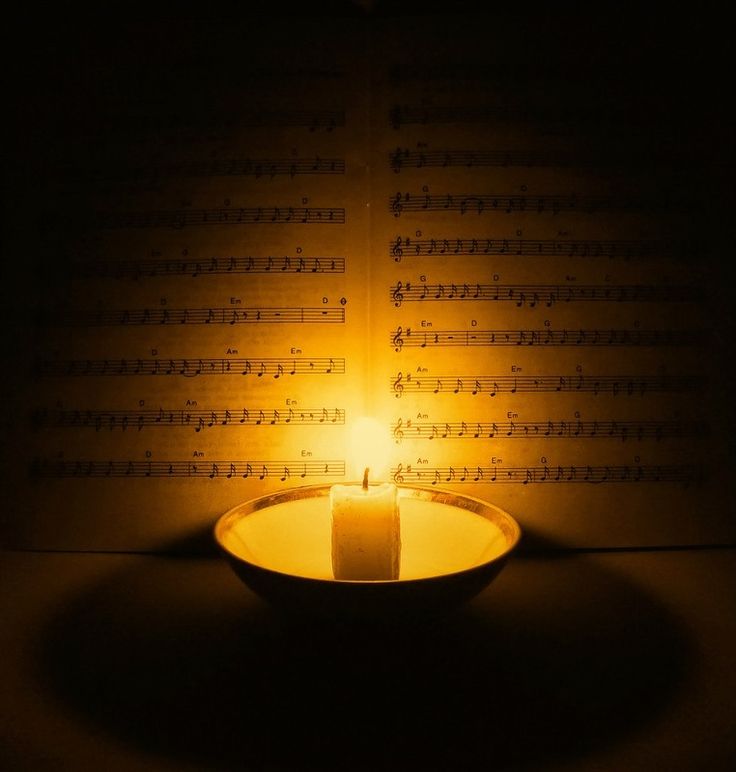Фото Горящая свеча освещает нотный лист