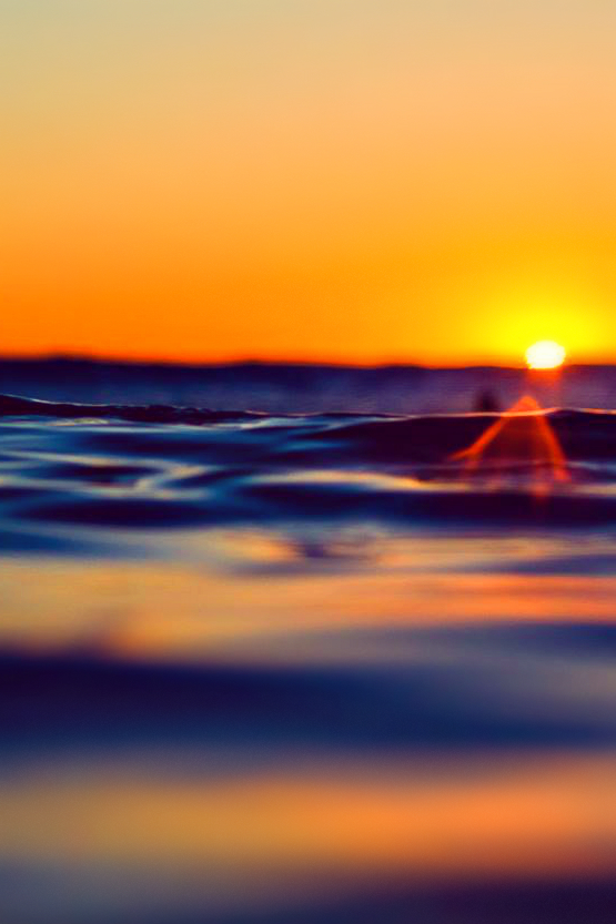 Фото Поверхность воды, с заходящим вдали солнцем