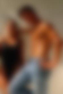 Фото Обнаженный до пояса мужчина в джинсах, стоит рядом с закрывшей глаза девушкой, в черном купальнике