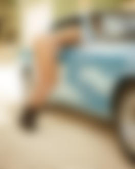 Фото Обнаженная девушка стоит, наполовину заглядывая в окошко автомобиля