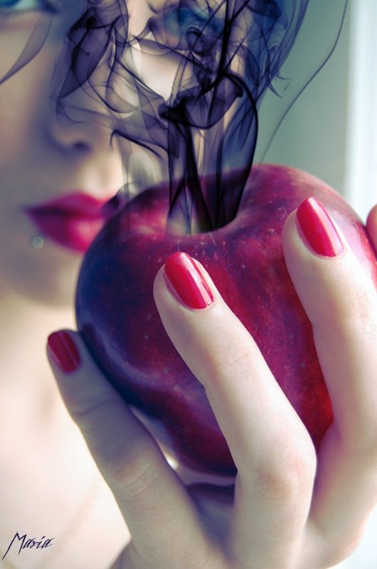 Фото Девушка держит яблоко, из которого идет черный дым