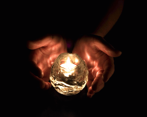 Фото Горящая свеча в баночке между руками человека