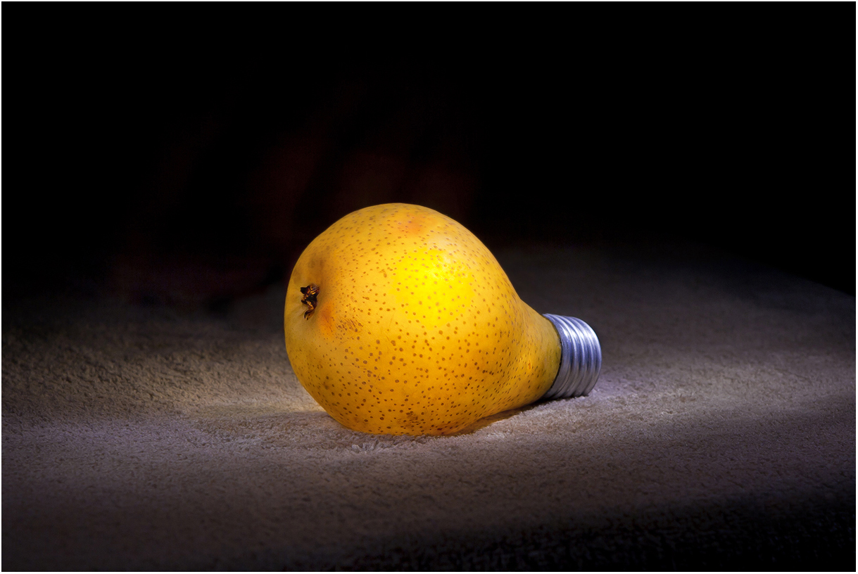 Фото Желтая груша лежит на столе с патроном, в виде электрической лампочки