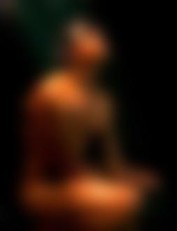 Фото Обнаженный мокрый мужчина сидит поджав ноги на черном фоне с бликами, подняв вверх голову