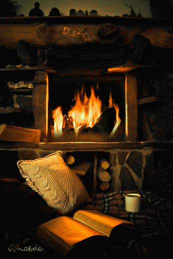 Фото У горящего камина на постели лежит подушка, открытая книга и чашка