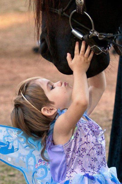 Фото Девочка пытается поцеловать коня
