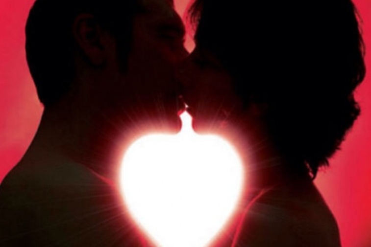 Фото Между целующимися мужчиной и женщиной лучи света образовали фигуру сердца