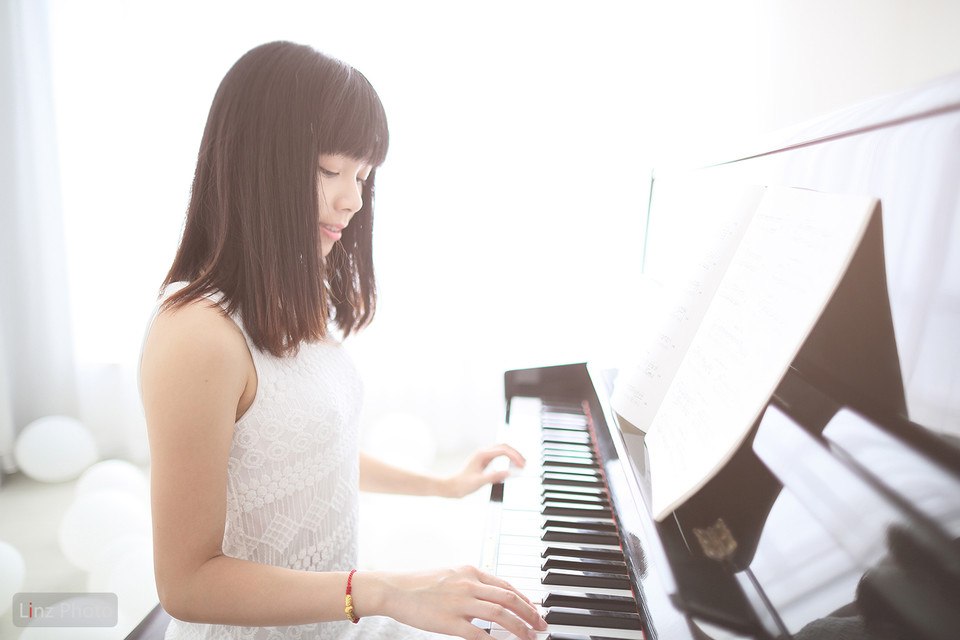 Фото Девушка в белом платье сидит на пианино и играет