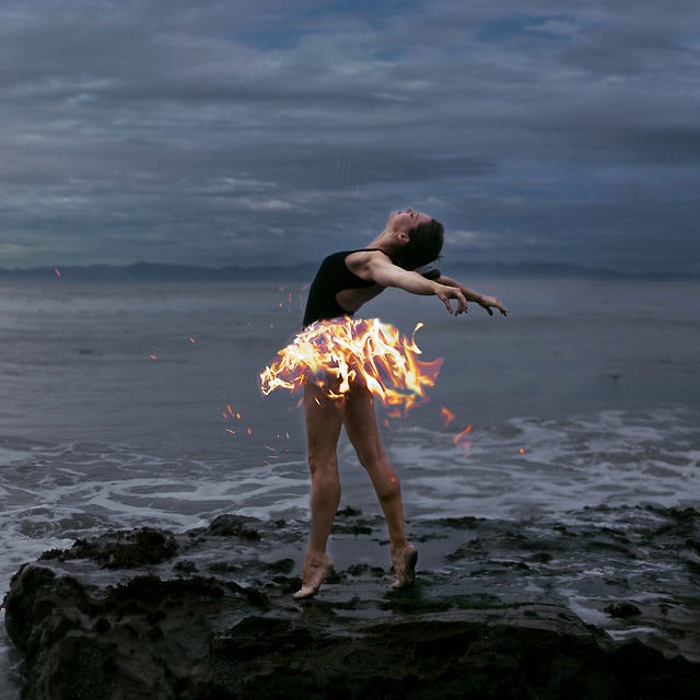 Фото Девушка с огненной юбкой, стоит на прибрежной скале, на фоне моря