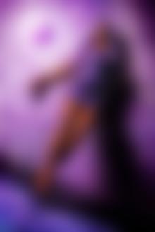 Фото Измазанная девушка в сиреневом платье, с сиреневыми волосами, стоит на сиреневом полу на фоне сиреневой абстрактной стены с сиреневым шаром, ву Стефан Геселл