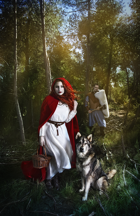 Фото Красная шапочка с корзинкой в руке стоит на траве рядом с волком, позади них стоит мужчина с топором, by Rebecca Grey