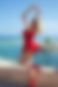 Фото Девушка в красном платье стоит на фоне моря