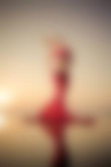 Фото Девушка блондинка в яркой красной юбке и в красном купальнике стоит на берегу моря, запрокинув голову назад, фотограф Александр Хромов