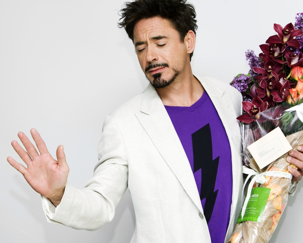 Фото Актер Роберт Дауни мл. / Robert Downey Jr. вытянув одну руку в перед, в другой держит букет цветов