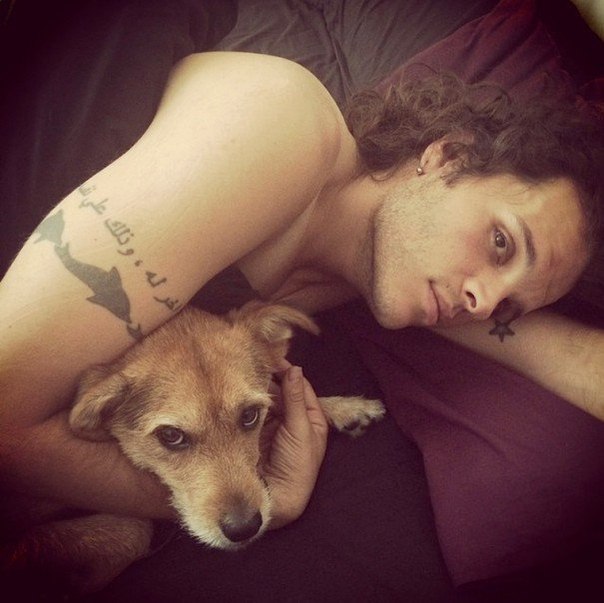 Фото Мужчина лежит на постели вместе с собакой