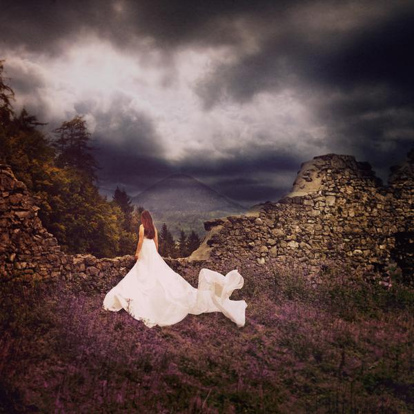 Фото Девушка в длинном белом платье стоит на фоне природы