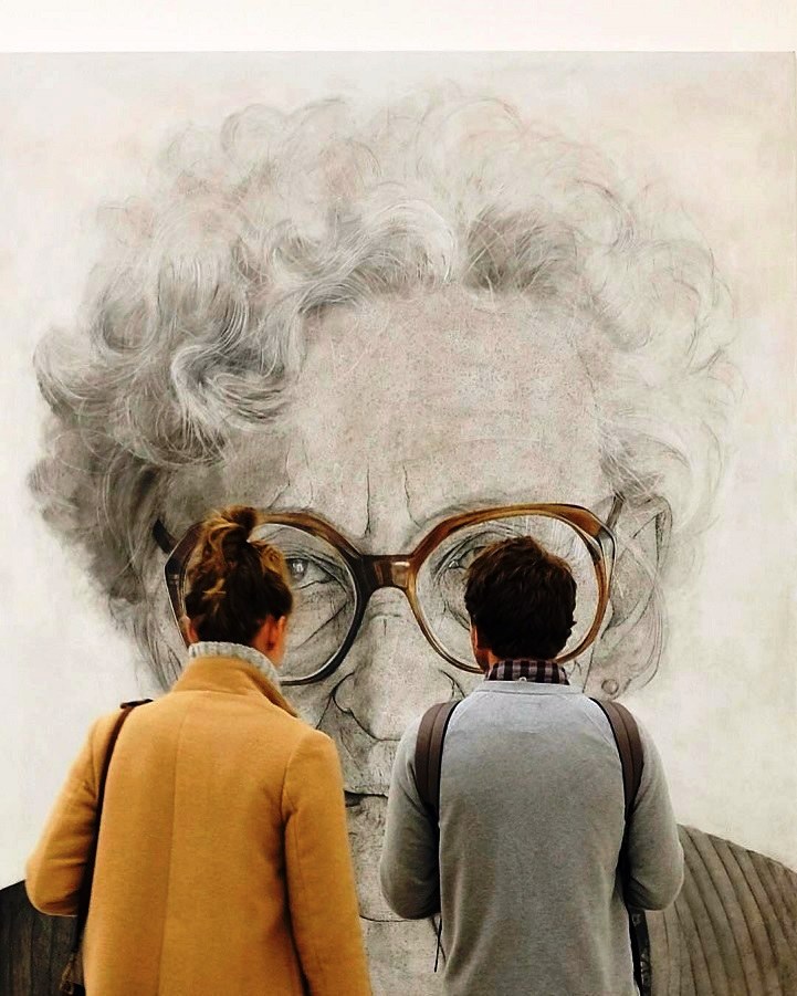 Фото Девушка и парень рассматривают баннер с пожилой женщиной в очках
