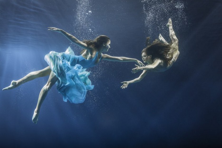 Фото Девушки танцующие под водой, на фоне воздушных пузырьков и сине-серой толщи воды. Фотограф Майя Алмейда / Maya Almeida