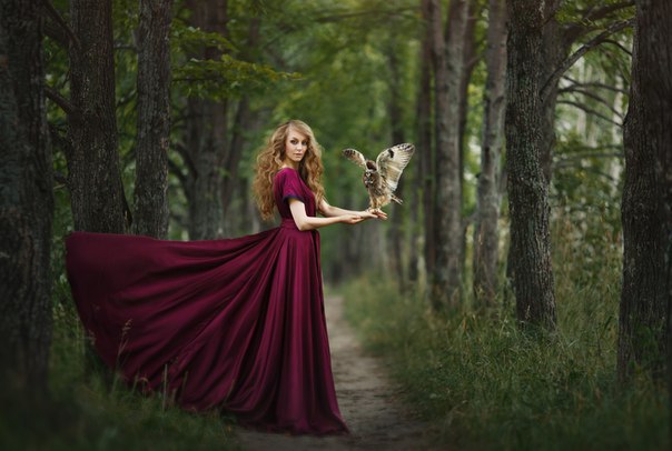 Фото Девушка в бордовом платье с совой на руке стоит в лесу на дороге, фотограф Александра Калтыкова