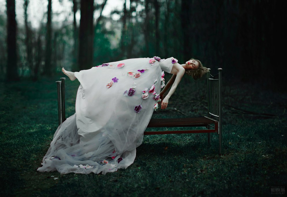Фото Девушка в длинном белом платье в цветах парит в воздухе над кроватью, стоящей на поляне среди леса, фотограф Светлана Беляева