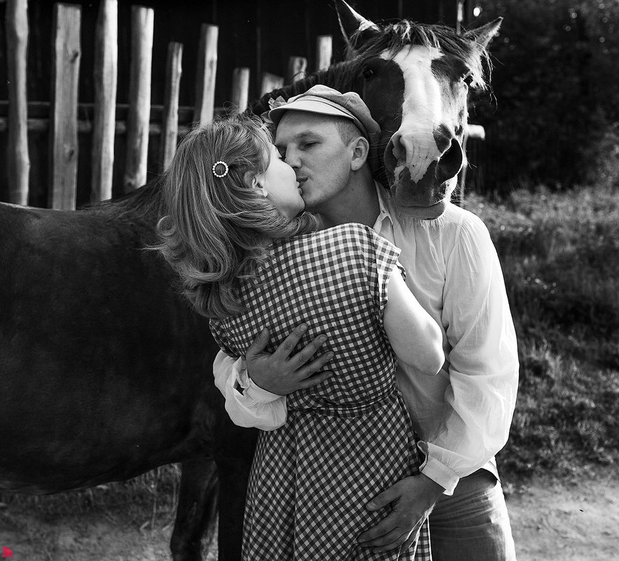 Фото Мужчина в кепке, в белой рубашке обнимает и целует девушку в клетчатом платье, рядом с ними стоит конь, фотограф Ежъ Осипов