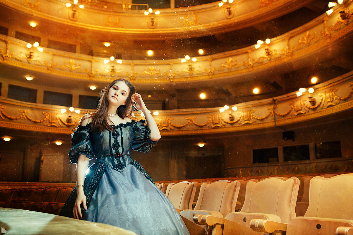 Фото Девушка с длинными темными волосами в длинном вечернем ретро-платье стоит в пустом оперном зале, фотограф Ежъ Осипов